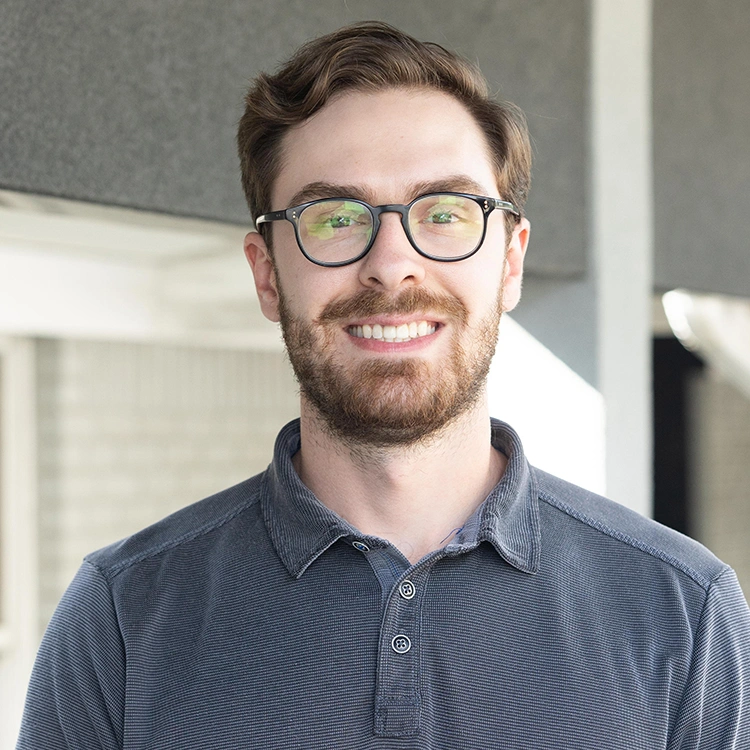 Man wearing glasses and blue shirt smiling in dental office setting.