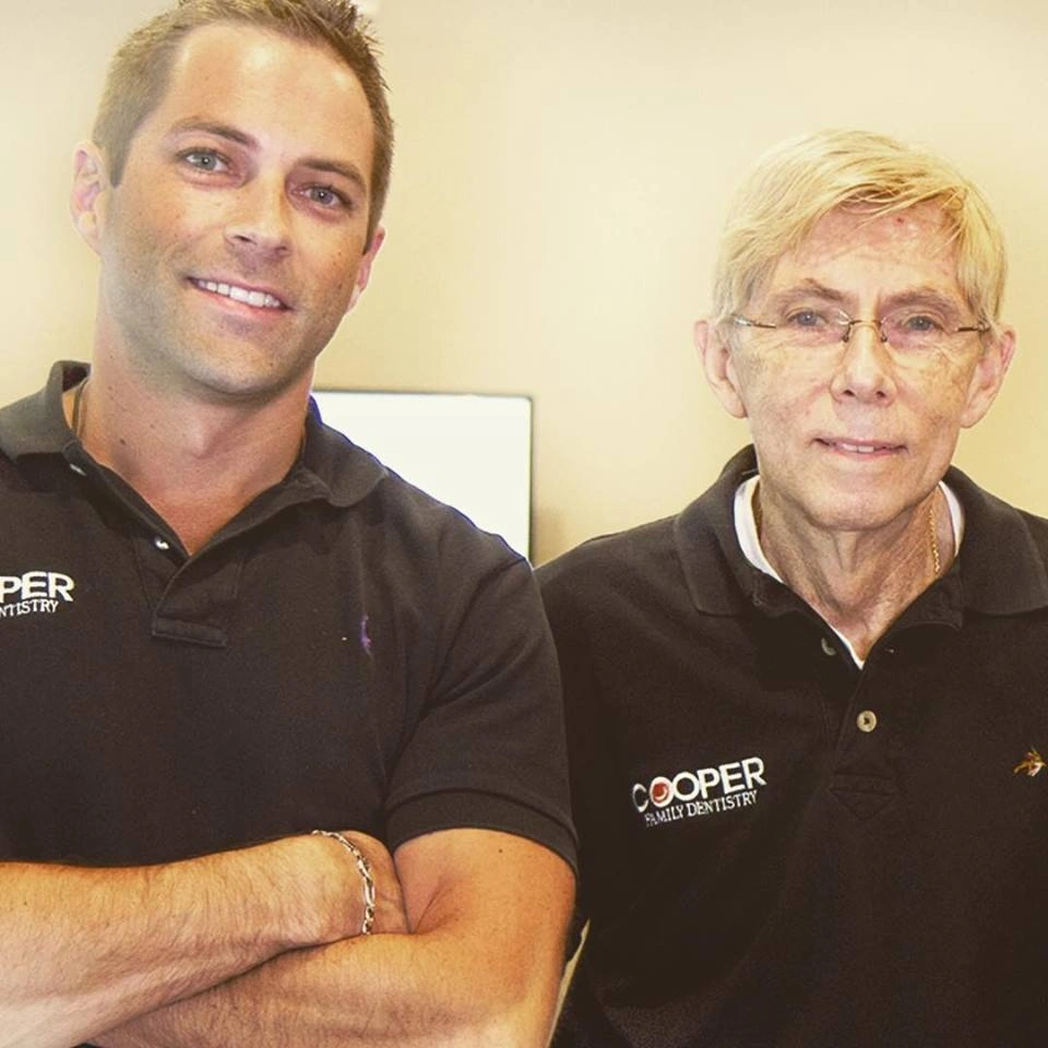 Two dental professionals in Cooper branded uniforms posing together in a clinic setting.