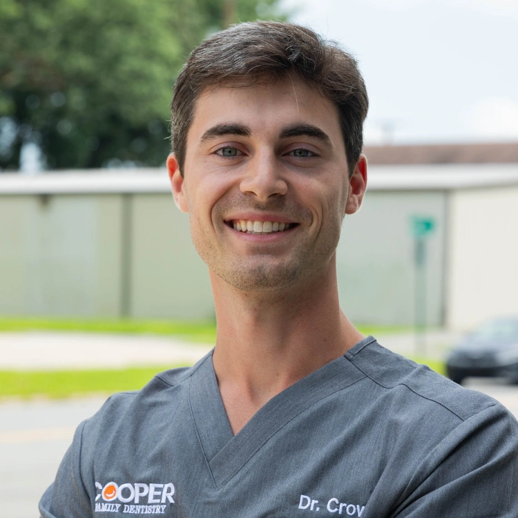 Dr. Croy smiling outdoors in scrubs at Cooper Family Dentistry clinic